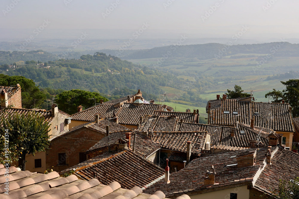 Naklejka premium Traditional terracotta rooftops of the medieval hilltop town of Montepulciano in Tuscany, Italy, overlooking the soft rolling countryside of the Province of Siena during autumn. 
