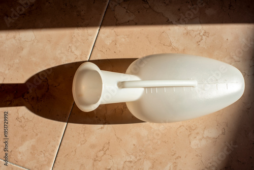 Plastic Medical Urinal Container on Floor – Healthcare and Hygiene Concept