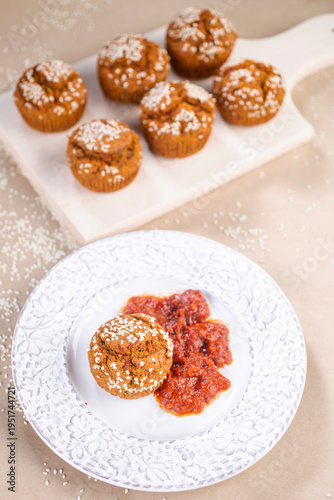 Proja sprinkled with sesame, served on a decorative white plate with a side of ajvar.