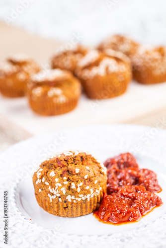 Proja sprinkled with sesame, served on a decorative white plate with a side of ajvar.