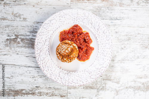 Proja sprinkled with sesame, served on a decorative white plate with a side of ajvar.