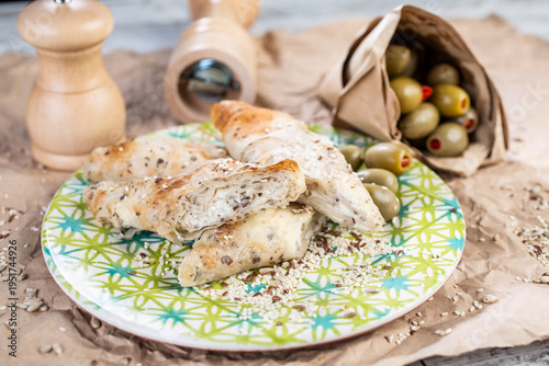 Roasted pieces of chicken served on a colorful plate, with the addition of olives and spice grinders in the background.