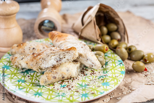Roasted pieces of chicken served on a colorful plate, with the addition of olives and spice grinders in the background.