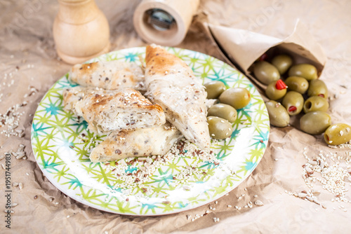 Roasted pieces of chicken served on a colorful plate, with the addition of olives and spice grinders in the background.