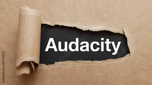 Close-up of torn kraft paper revealing the word Audacity