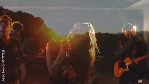 Singing lead singer gripping mic and whipping hair as riff starting at rehearsal, sunrise overlay