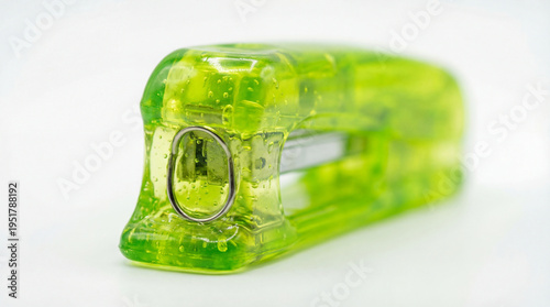 Translucent green gelatin stapler resting on minimalist white studio desk