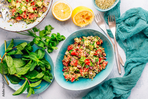 Colorful couscous salad with tomatoes and cucumber in rustic bowl, garnished with fresh mint