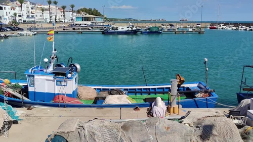 Fishing port of Las Casas de Alcanar in Catalonia, Spain. View of the boats with traditional fishing gear moored at the dock. Smooth camera movement: Panning Left.