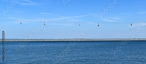 Lisbon cable car system transports passengers over the Tagus River with Vasco da Gama Bridge in background, Portugal