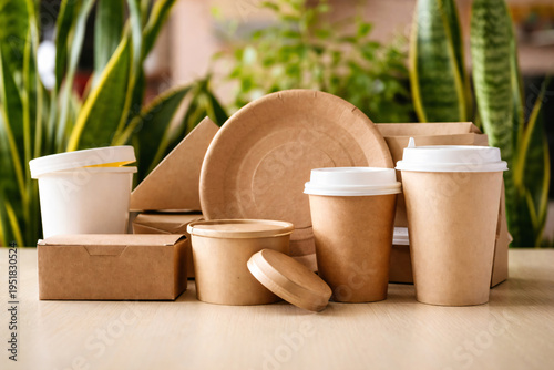 Eco-friendly disposable paper tableware with green plants background, sustainable food packaging concept