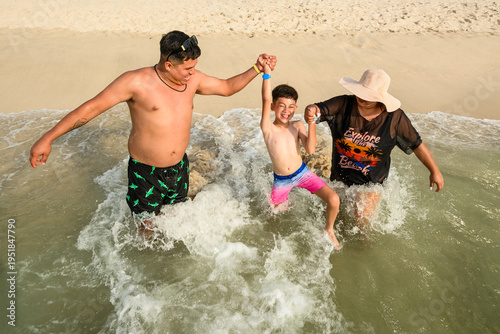 Happy parents playing with their young son in the ocean waves on a Mexican beach