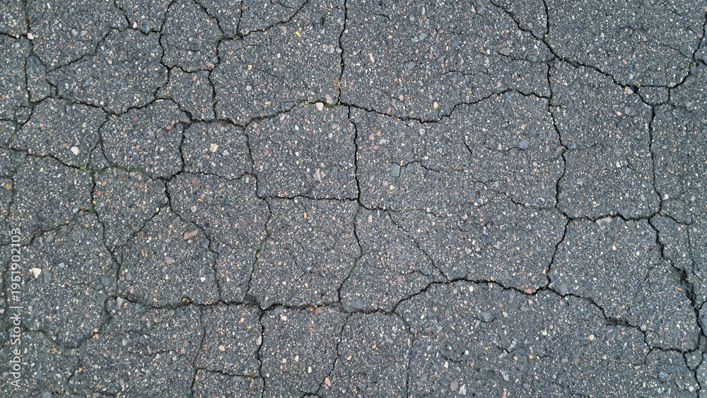 Obraz premium Close-up of cracked asphalt pavement texture