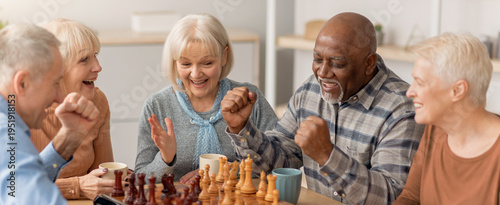 Fotografie Five seniors are gathered around a table playing chess
