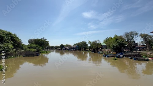 Muddy Sangker river with stilt houses along the banks between Tonle Sap Lake and Battambang Cambodia. Daily activities of local residents in Southeast Asia.