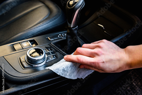 Close-up of male hand wiping car dashboard with microfiber cloth for cleaning. Concept of vehicle hygiene, interior maintenance and car detailing.