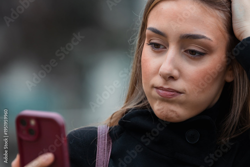 young woman looking at her mobile phone, looking worried