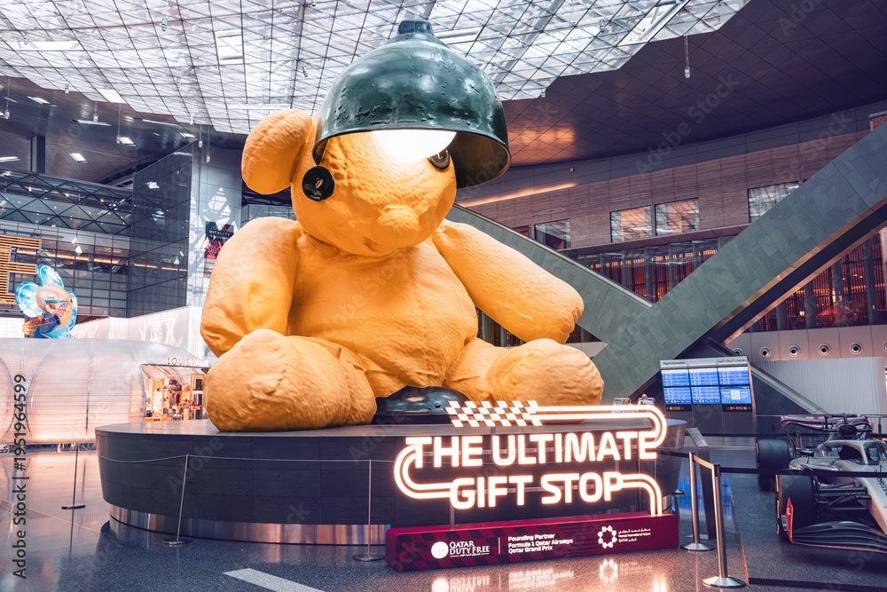 Fototapeta premium 2 December 2025, Doha, Qatar: Lamp Bear artwork and a Formula 1 car are on exhibit at Hamad International Airport