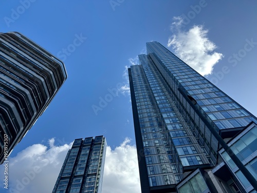 Obraz na płótnie Skyscraper Perspective: An upward view of tall glass skyscrapers reaching toward a blue sky representing modern corporate architecture