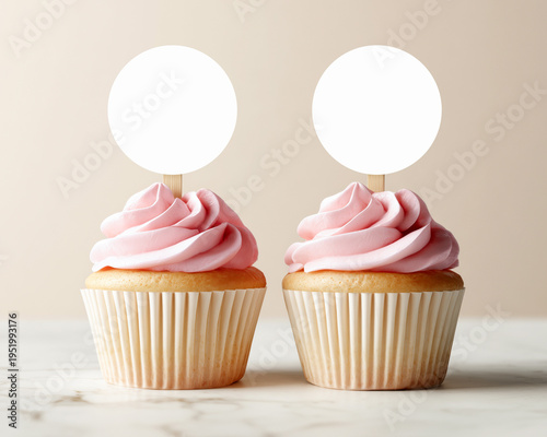 Two cupcakes with  pink frosting and blank round toppers