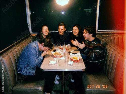 Vintage Flash Photography of Friends Laughing in a Retro Diner Booth Eating Fries