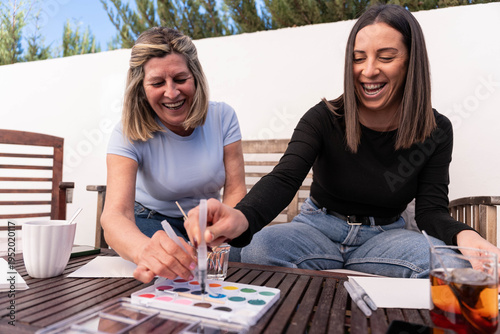 Schilderij op canvas Mother and adult daughter laughing while painting watercolors outdoors