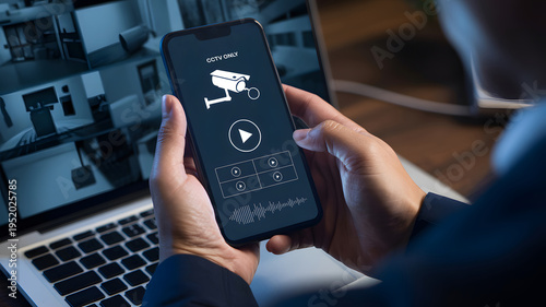 Man monitoring home security camera system on smartphone app, displaying live CCTV footage on laptop screen, ensuring digital surveillance and smart house protection with modern technology