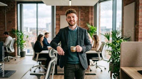 Young man smiling while holding a coffee mug in modern office  