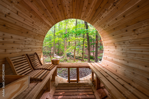 Foto Wooden barrel sauna interior with forest view, bench seating and wellness retrea