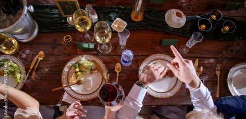 Panoramic view of busy table at a wedding reception complete with food, wine and hands.