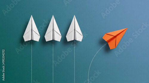 A distinctive orange paper airplane courageously deviates from the uniform path of white paper planes, illustrating unique vision and innovation.