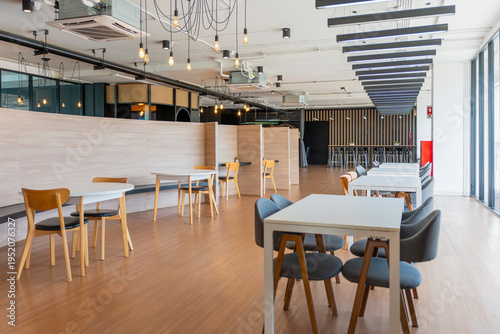 Modern empty coworking space interior with wooden tables and stylish lighting, Spacious corporate breakroom or library interior with various seating arrangements