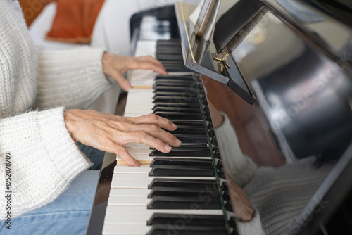 Close up of mature woman hands playing piano at home.