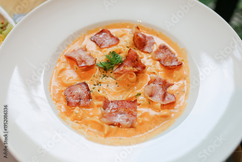 spaghetti carbonara on white dish, Creamy pasta carbonara with bacon bits and fresh parsley garnish served in white bowl. Classic Italian cuisine dish with rich sauce and herbs for dinner.