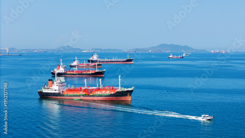 LPG gas and oil tanker ships anchored in the ocean, with a fast patrol boat in the foreground. Global energy transport, war energy crisis, and Strait of Hormuz blockade concept.
