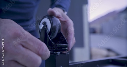 Closeup on man's hands screwing wheel onto something