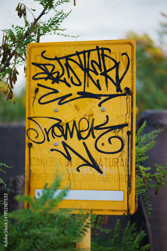 yellow street sign vandalized with graffiti and street art