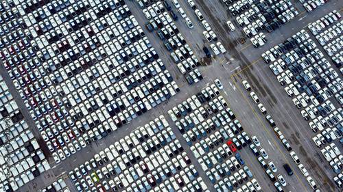 Fotografía Aerial view of large car parking lot filled with new vehicles arranged in grid pattern at logistics distribution center during daytime, symbolizing automotive industry supply chain