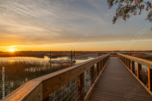 фотографія Sunset over marshland with wooden walkway and calm water at evening in nature in