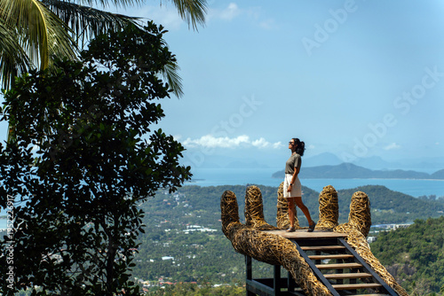 Tourist standing on Giant Hand Viewpoint (Overlap Stone Viewpoint) overlooking tropical landscape on Koh Samui