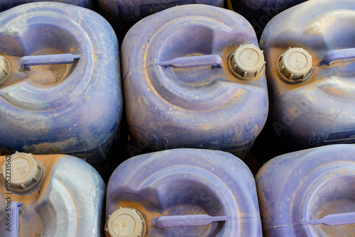 Photos Neatly stacked blue plastic jerrycans, each with a secure screw cap, highlightin