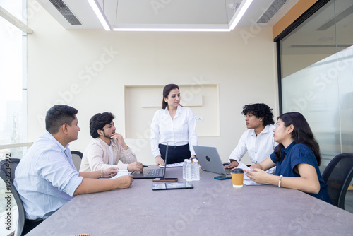 Young indian business people or office employees sitting in meeting room discuss work. Corporate job. Teamwork.