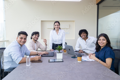 Young successful indian business people or office employee sitting in meeting room looking at camera. Corporate job. Teamwork.