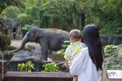 Photos Mother holding baby visiting elephant at zoo