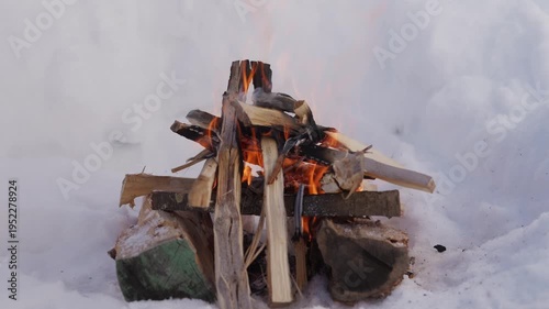 Wallpaper Mural Firewood stacked in a small campfire burning inside a snow pit. Visible flames rise between the wooden logs while the fire burns in winter conditions. High quality 4k footage Torontodigital.ca