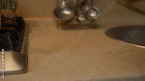 Wallpaper Mural A glass plate is gently placed on a kitchen table near a sink. Everyday domestic moment with neutral interior, soft light, and simple home lifestyle atmosphere. High quality 4k footage Torontodigital.ca