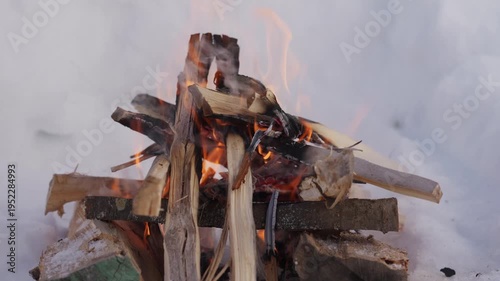 Wallpaper Mural Close view of a winter campfire burning stacked firewood inside a snow pit. Bright orange flames flicker between wooden logs while smoke rises in cold outdoor conditions. High quality 4k footage Torontodigital.ca
