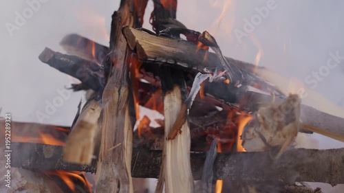 Wallpaper Mural Close view of flames rising from burning firewood in a small winter campfire. The fire burns inside a snow pit while smoke drifts upward in the cold air. High quality 4k footage Torontodigital.ca