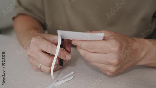 Wallpaper Mural Close-up of scissors cutting a curved strip from a white paper sheet. Hands carefully guide the blades as the thin paper strip bends while being separated from the sheet. High quality 4k footage Torontodigital.ca