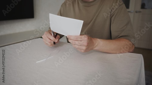 Wallpaper Mural Medium close view of a man cutting a sheet of white paper with scissors while sitting at a table. Small paper strips appear on the table as the blades move through the material. High quality 4k Torontodigital.ca